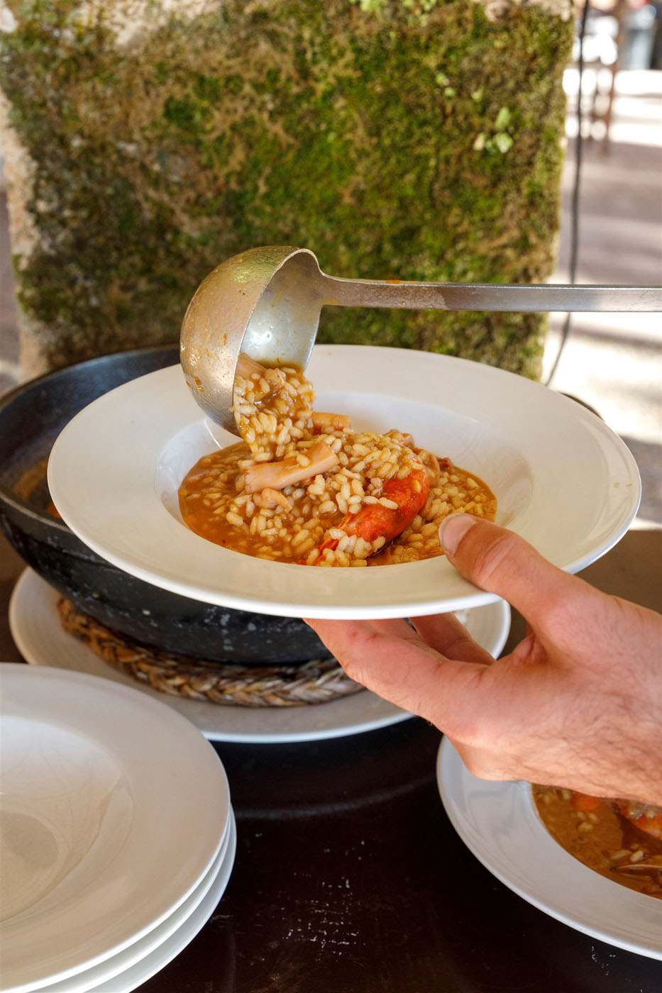 Camarero sirviendo arroz caldoso de marisco recién hecho en el restaurante Son Terrassa