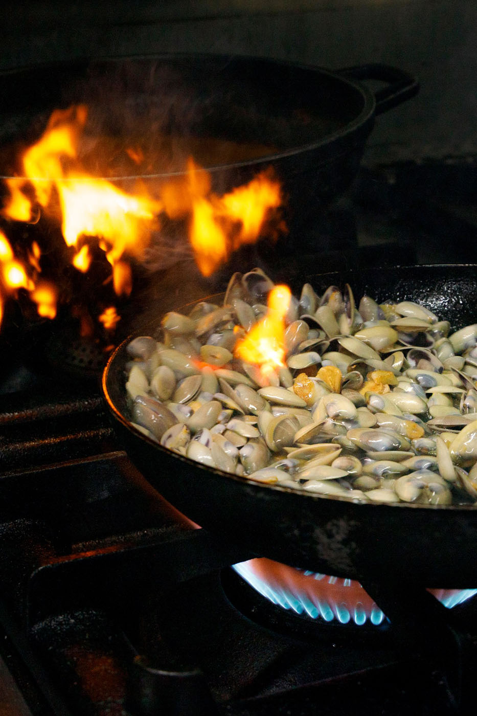 Almejas salteándose en sartén con fuego en la cocina del restaurante Son Terrassa, cocina tradicional